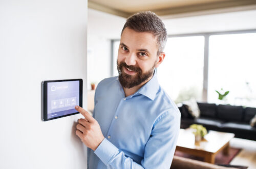 Mann, der auf ein Tablet mit Smart Home Control System zeigt