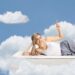 Frau auf Bett mit Wolken im Hintergrund