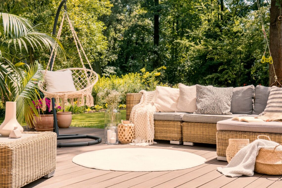 Gemuetlicher Outdoor-Loungebereich mit Rattansofa und Haengesessel als offene Alternative zum Pavillon im Garten