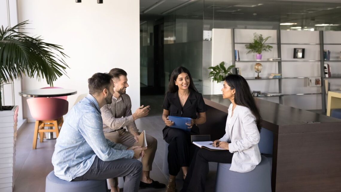 Business-Team sitzt im offenen Meetingbereich eines Tagungshotels in NRW und bespricht Details zur bevorstehenden Veranstaltung