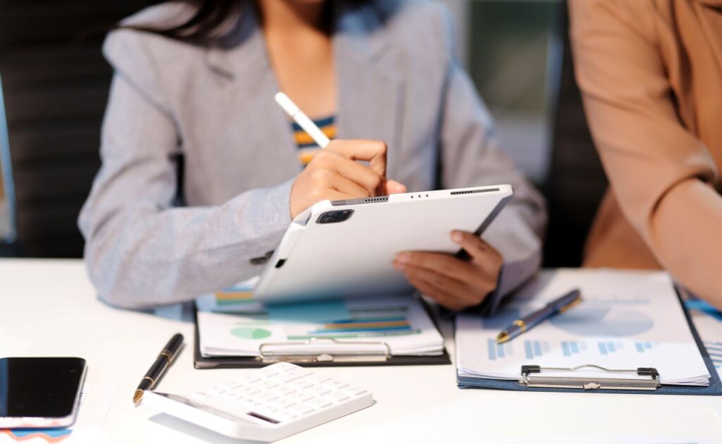 Frau analysiert Eventdaten auf Tablet und plant ein Business-Event im Tagungshotel NRW – moderne Konferenzvorbereitung mit Zahlen und Charts