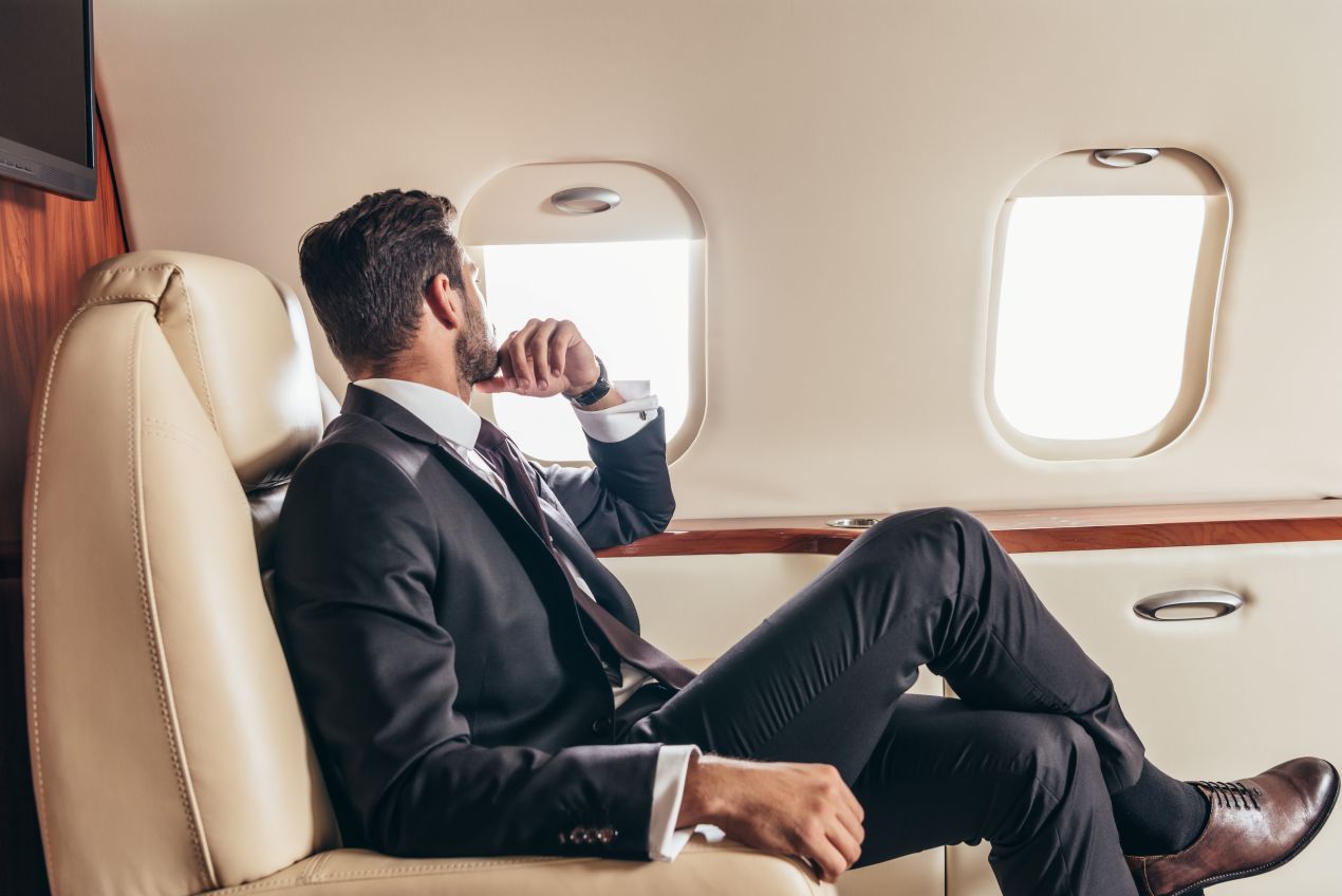 Geschaeftsmann sitzt entspannt im Sessel der Emirates Business Class und blickt aus dem Fenster