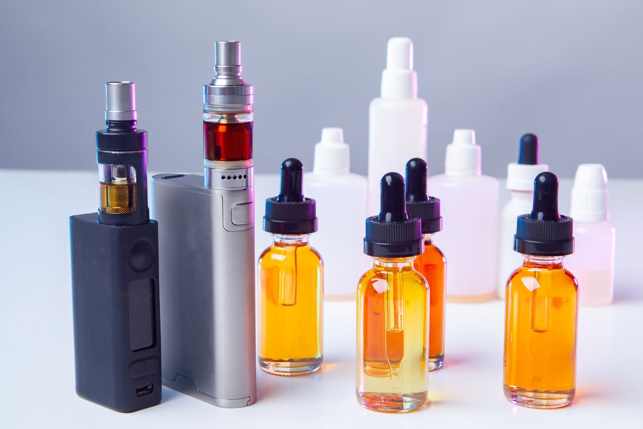 Verschiedene E-Zigaretten und Liquids auf weißem Tisch, Fokus auf Elfliq Liquid Auswahl