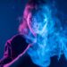 Frau dampft mit E-Zigarette in blauem Licht und testet Elfliq Liquid Geschmack