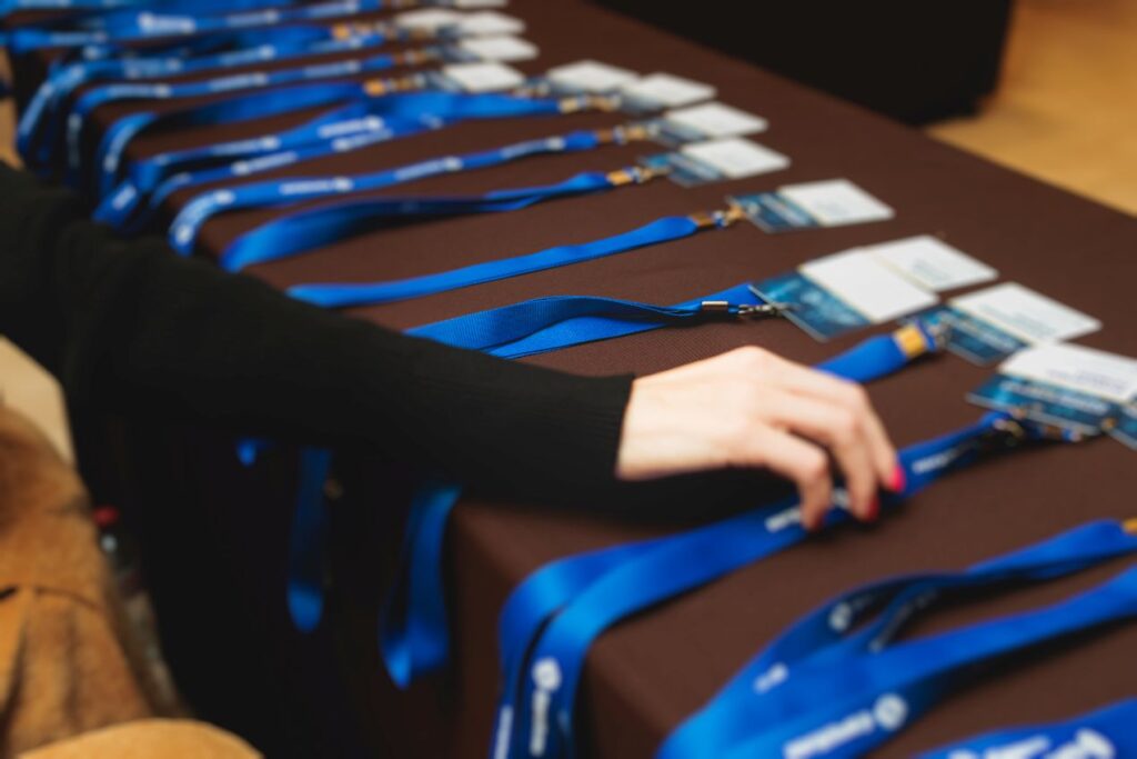 Person greift nach Namensschild bei Event-Check-in in einem Tagungshotel in NRW – Konferenzvorbereitung mit blauen Lanyards