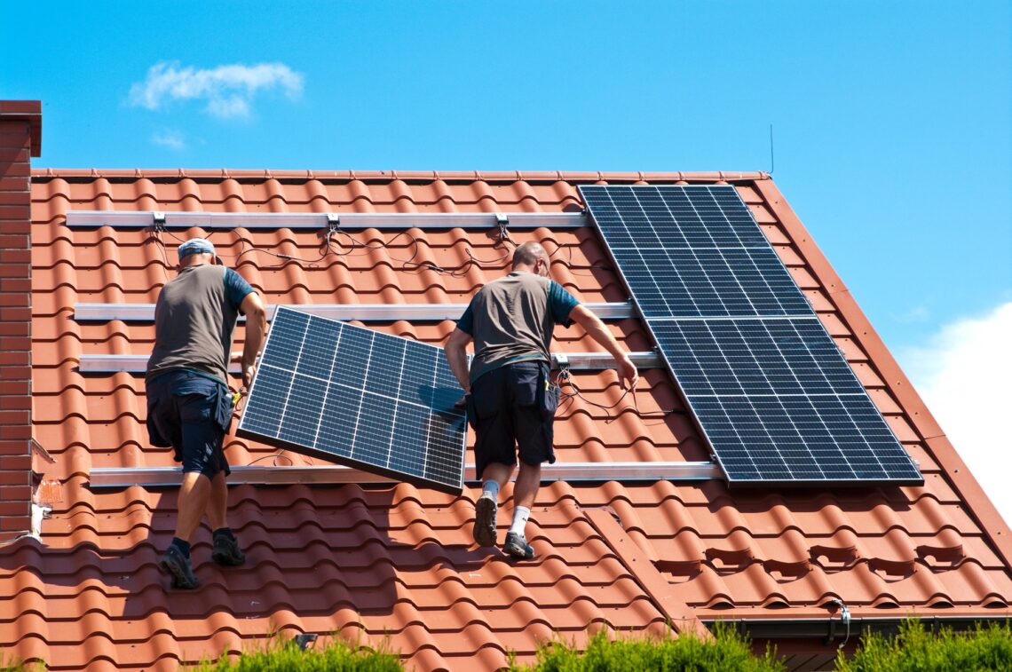 Handwerker installieren Solarpanels auf einem Hausdach | Batteriewechselrichter