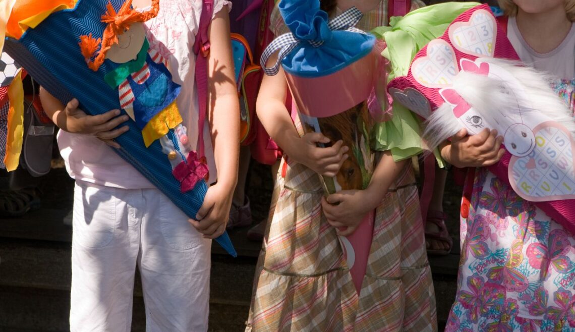 Kinder mit bunten Schultueten beim Schulanfang in der grundschule berlin, festliche Kleidung und Einschulungsfeier im Freien