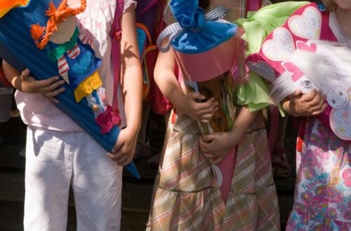 Kinder mit bunten Schultueten beim Schulanfang in der grundschule berlin, festliche Kleidung und Einschulungsfeier im Freien