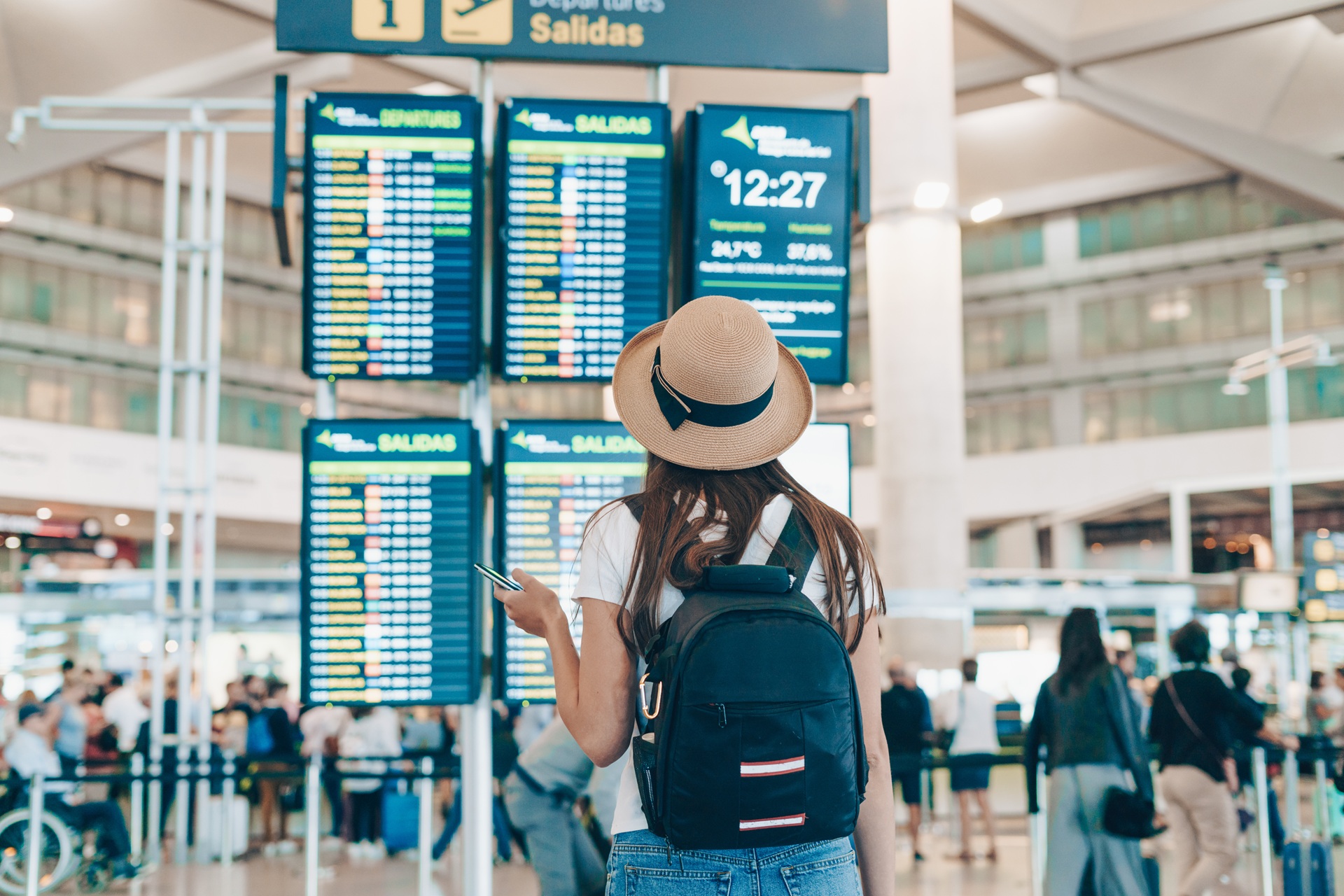 Person mit Hut vor Abflugtafel | Flughafen Shuttle Frankfurt